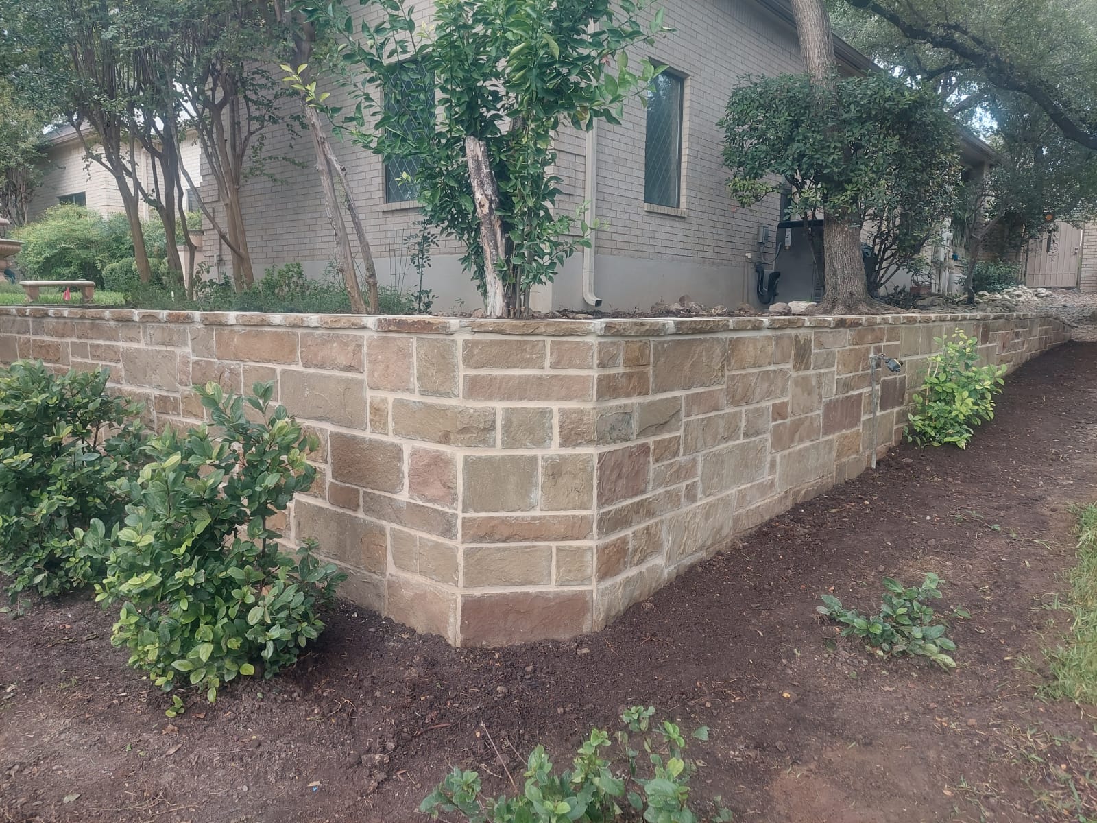 Stone retaining wall in a landscaped backyard